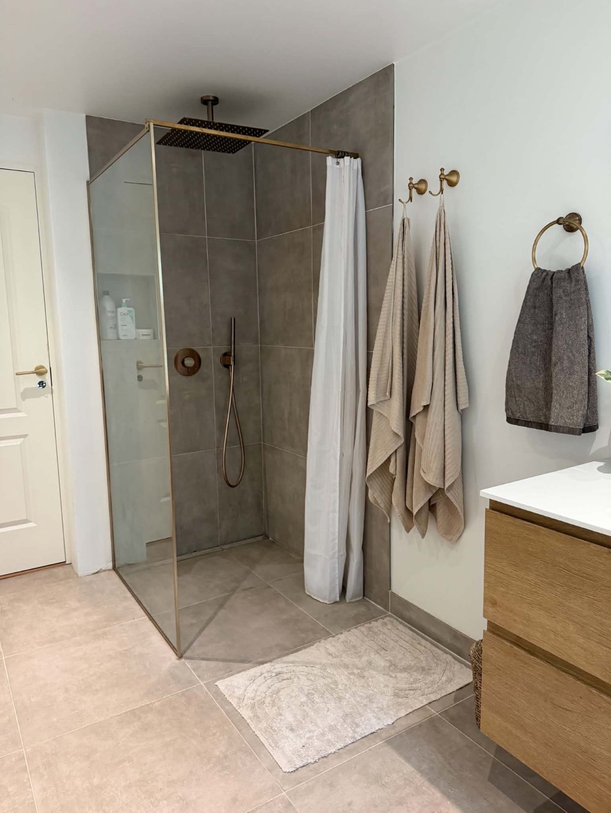 Badeværelse efter renovering – brusenische med glasvæg og regnbruser i messing